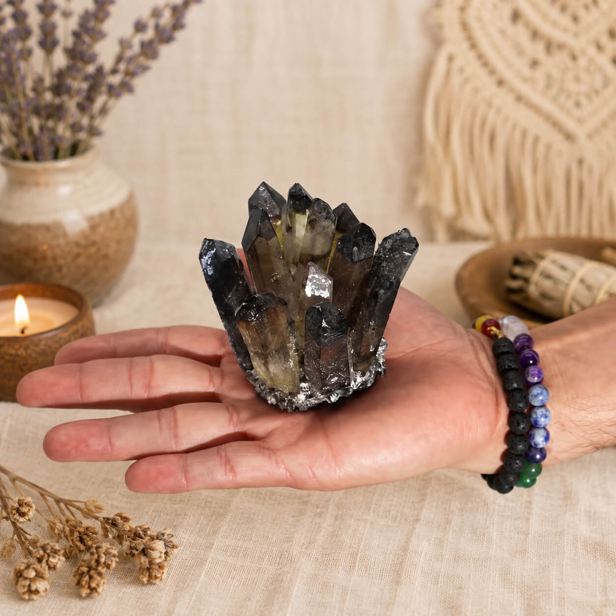 Grappe de quartz fantôme fumé tenue dans une main avec bracelets en pierres naturelles