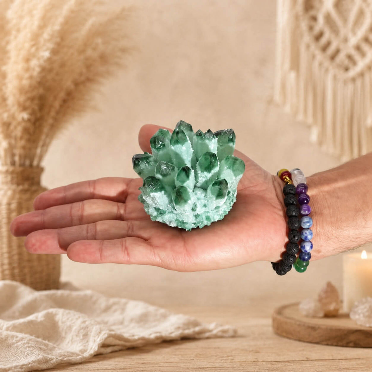 Grappe de quartz fantôme vert tenue dans une main avec bracelets en pierres naturelles