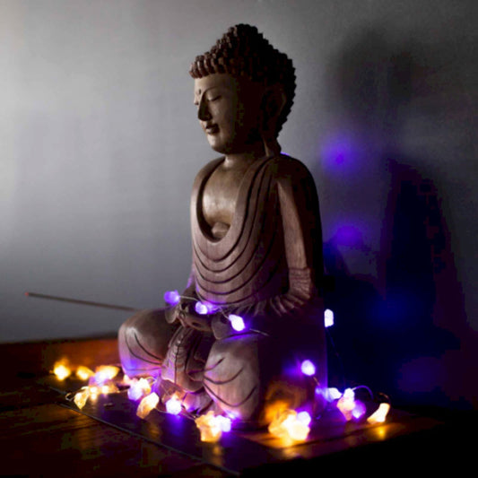 Une statue de Bouddha entourée d'une guirlande lumineuse USB, agrémentée de pierres naturelles.