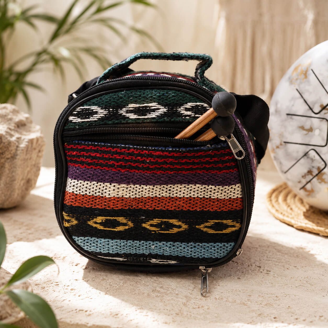Housse de transport tissée ethnique multicolore avec mailloches en bois glissées dans la poche zippée, fournie avec le tongue drum.