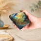 Labradorite naturelle polie tenue dans une main, reflets dorés visibles