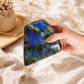 Grande labradorite polie tenue dans une main, reflets bleus visibles