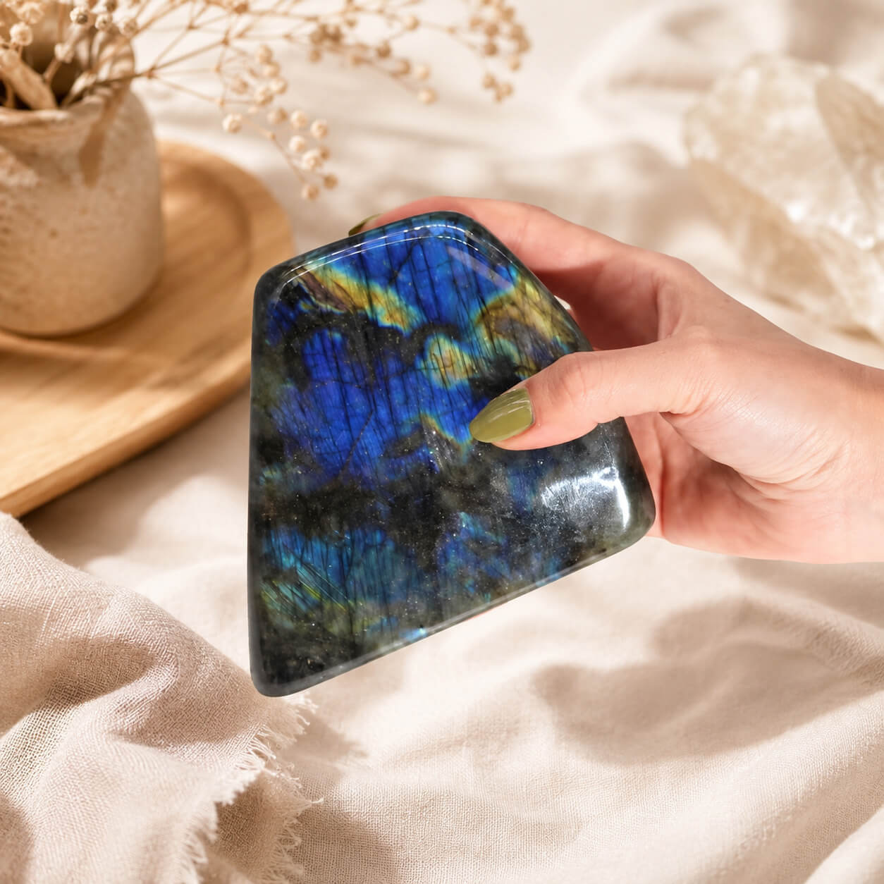 Grande labradorite polie tenue dans une main, reflets bleus visibles