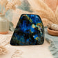 Grande labradorite polie aux reflets bleus et dorés posée sur un plaid