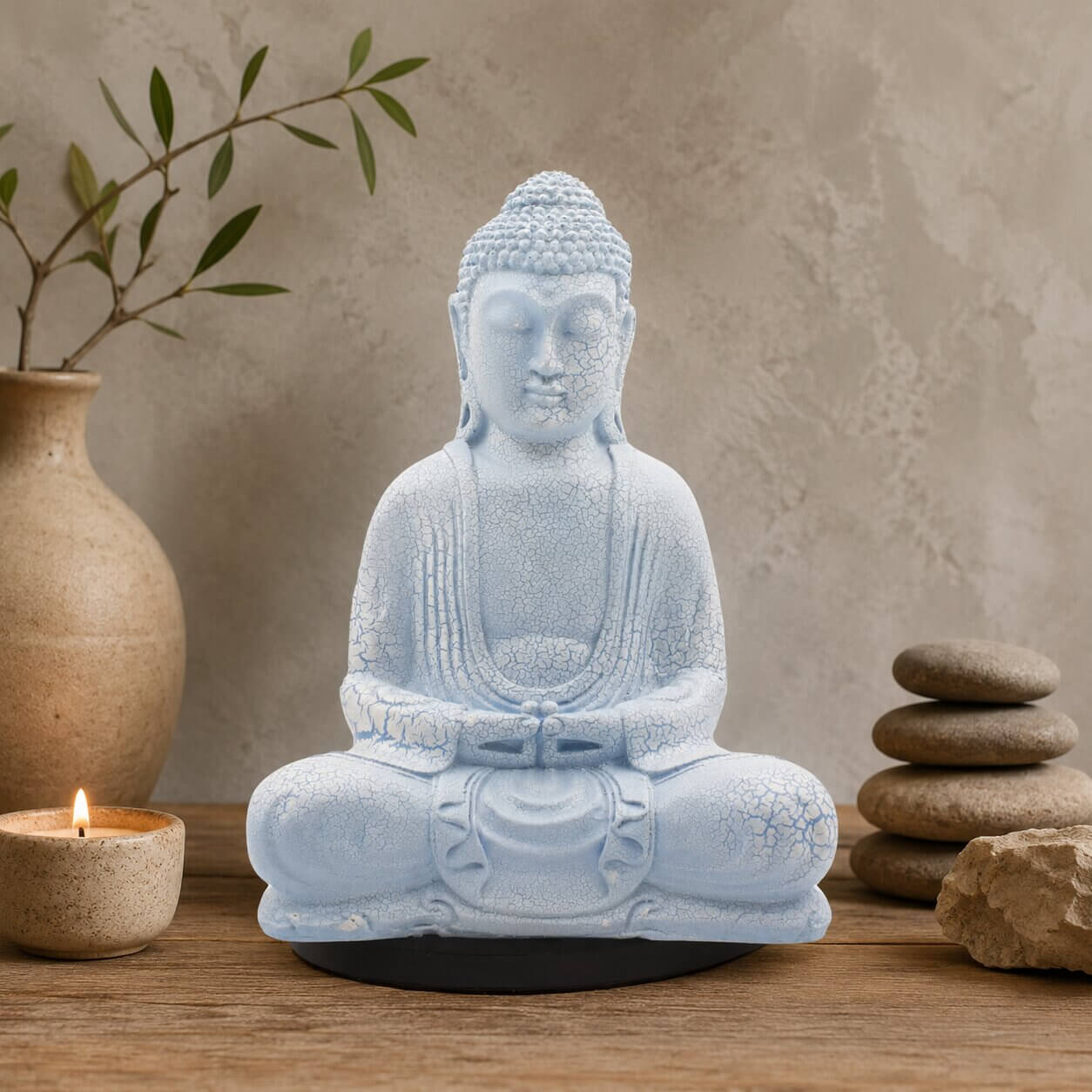 Lampe Bouddha bleu ciel craquelée éteinte sur socle ovale noir en décor naturel.