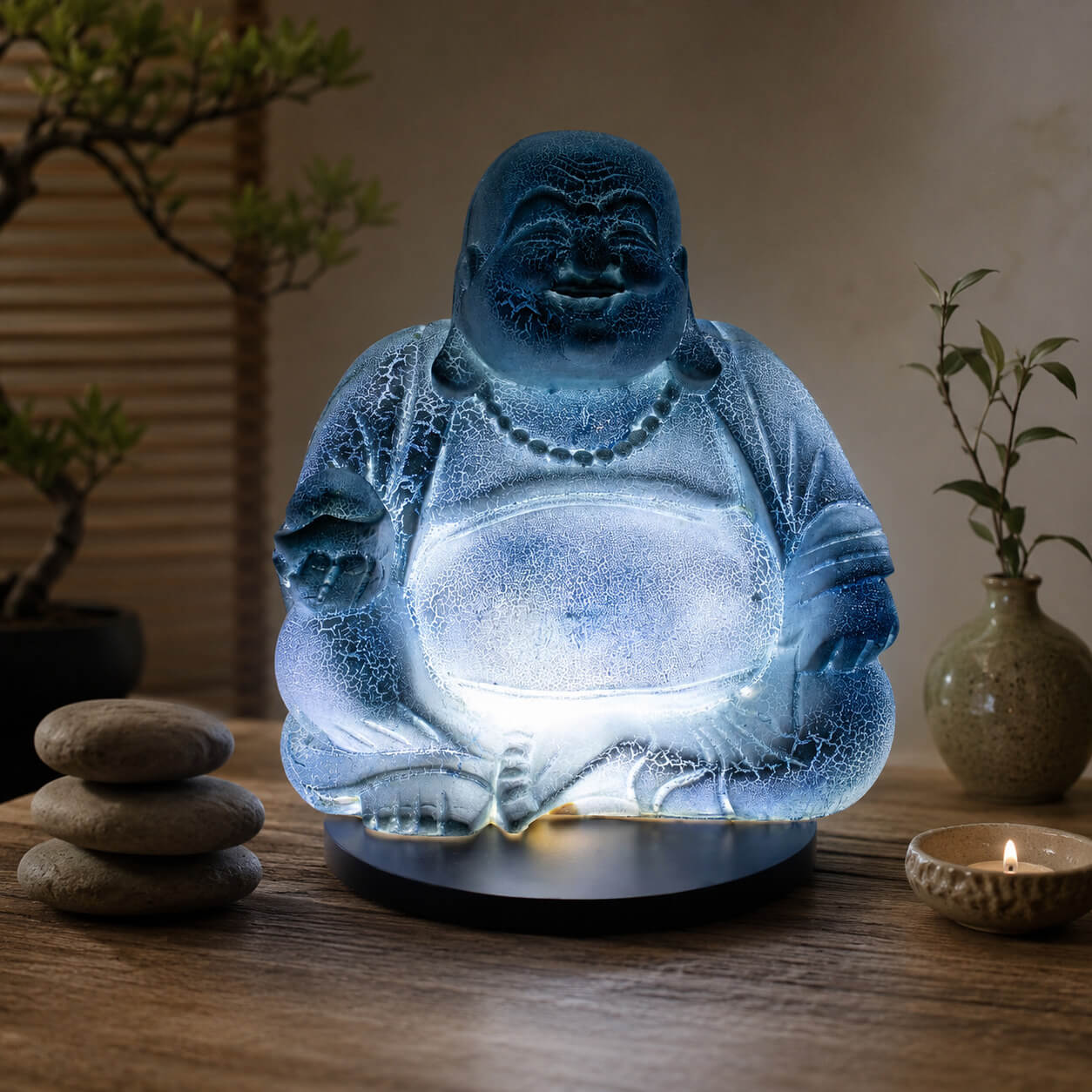 Lampe Bouddha rieur bleu ciel craquelée allumée dans une ambiance zen aux bambous.