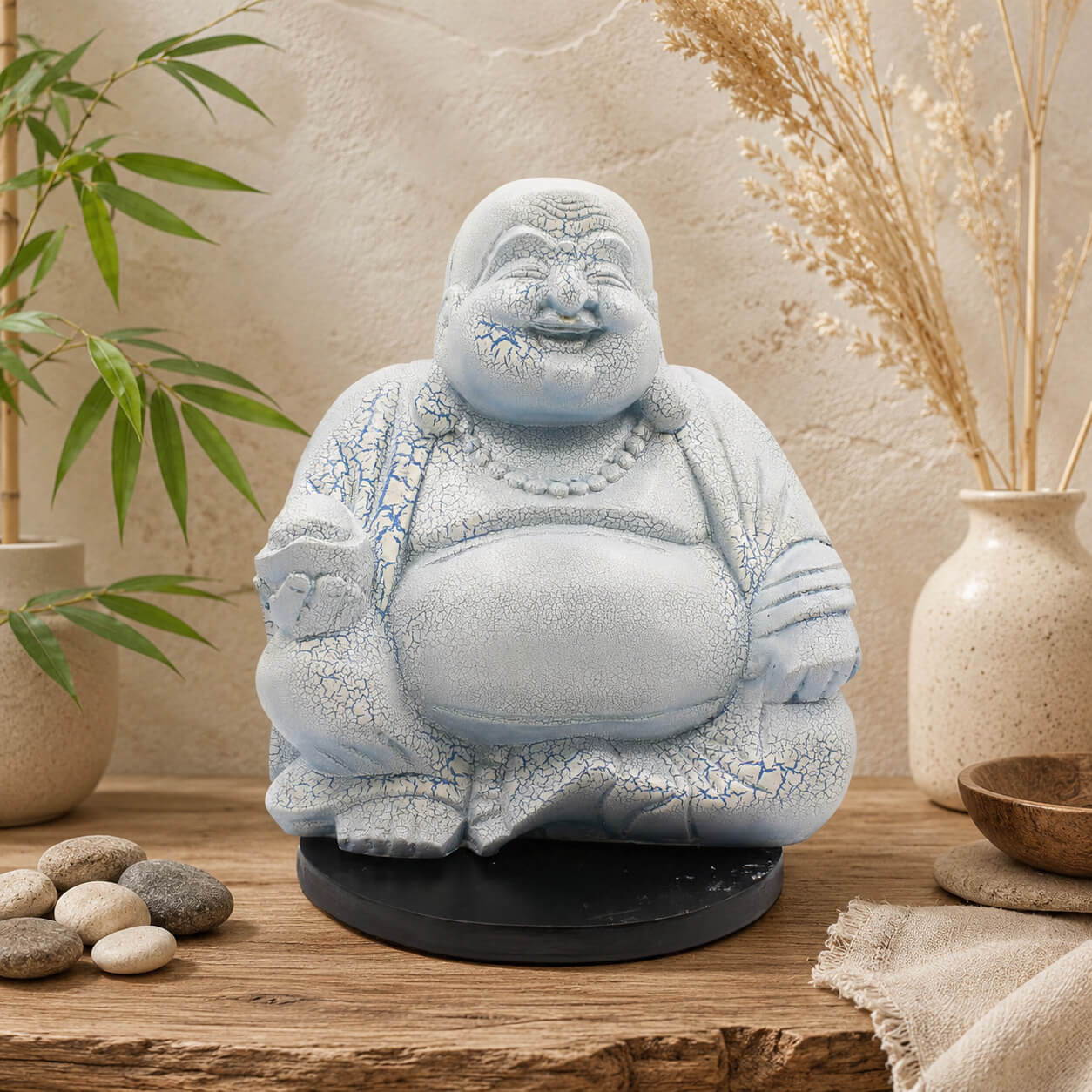 Lampe Bouddha rieur bleu ciel craquelée éteinte sur socle rond noir en décor naturel.