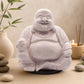Lampe Bouddha rieur lavande craquelée éteinte sur socle rond noir en décor naturel.