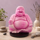 Lampe Bouddha rieur rose vif craquelée éteinte sur socle rond noir en décor naturel.
