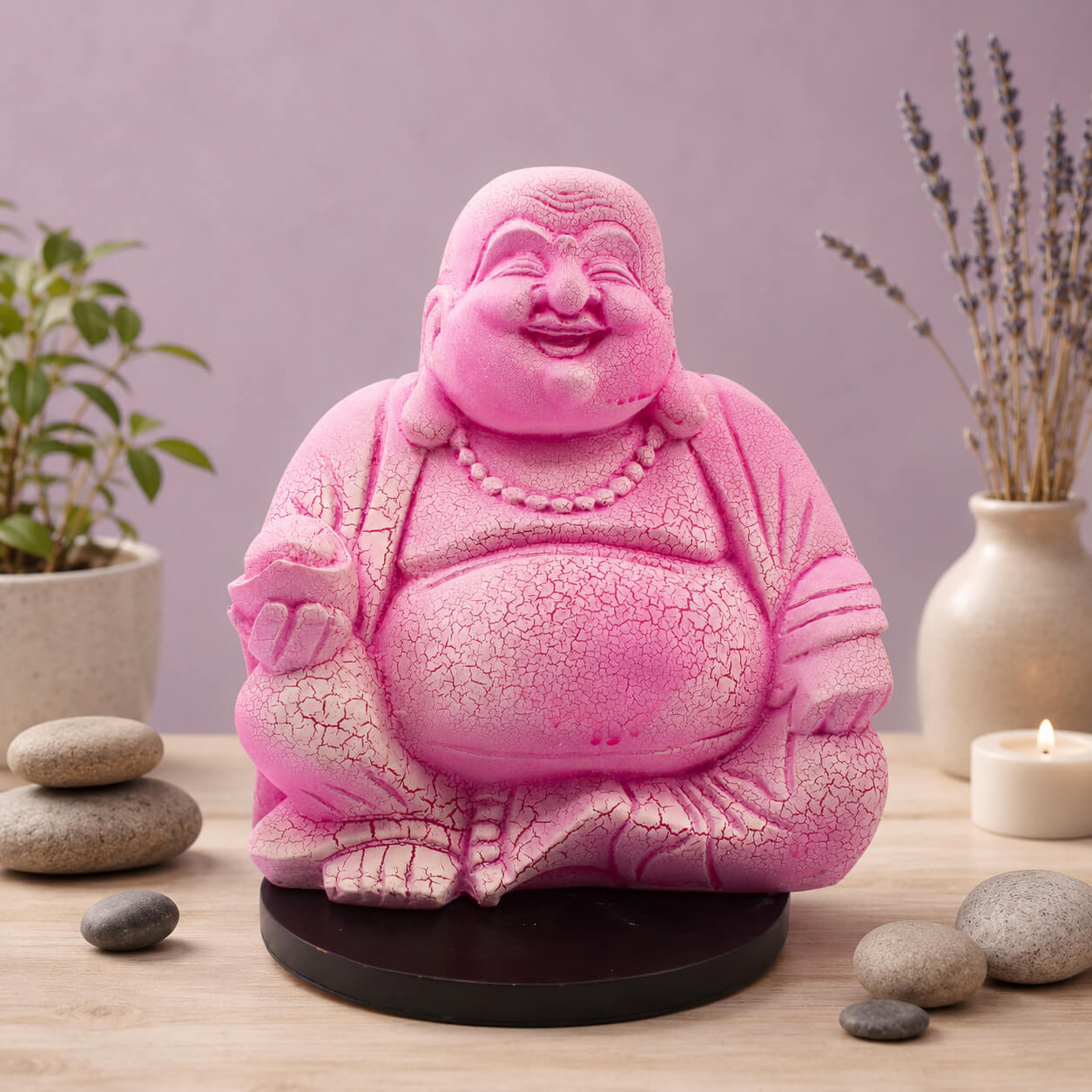 Lampe Bouddha rieur rose vif craquelée éteinte sur socle rond noir en décor naturel.