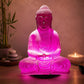 Lampe Bouddha rose cerise craquelée allumée diffusant une lumière rosée dans un coin méditation.