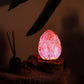 Lampe bouton de lotus rose aux reflets mauves allumée sur table de chevet zen.