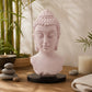 Lampe buste de Bouddha rose craquelée éteinte sur socle ovale noir en décor naturel.
