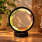 Lampe 7 chakras allumée, pierres de sept couleurs en cercle sur une commode en bois