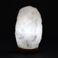 Lampe en cristal de roche blanc allumée diffusant une lumière douce et translucide à travers le quartz.