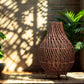 Lampe en rotin brun profond tressé Art du Tibet. Design artisanal élégant sur table.