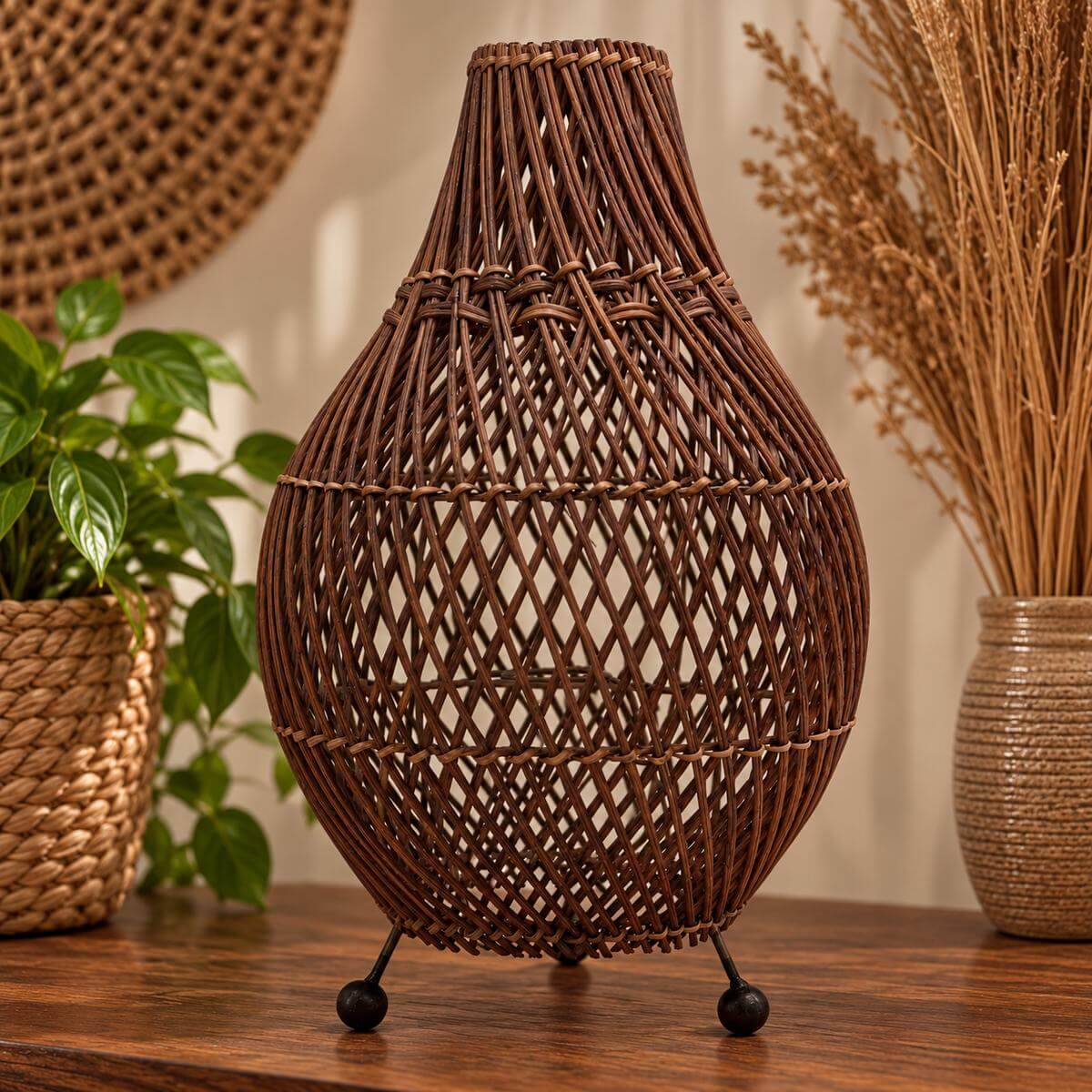 Lampe de table en rotin brun foncé à col étroit et treillis en losanges, sur trois pieds noirs, posée sur une console en bois
