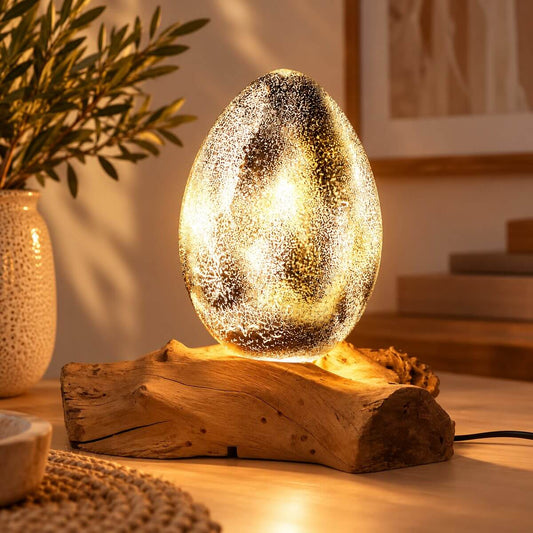 Lampe œuf de lave allumée sur bois flotté, révélant un fin craquelé doré et lumineux