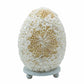 Lampe œuf nacré en coquillages assemblés en rosace florale sur socle blanc fond blanc