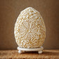Lampe œuf nacré en coquillages naturels posée sur table d'osier en ambiance naturelle