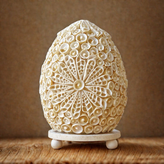 Lampe œuf nacré en coquillages naturels posée sur table d'osier en ambiance naturelle