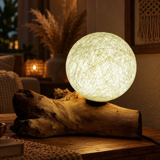 Lampe sphère lune ivoire allumée sur bois flotté, diffusant une clarté blanche et chaude