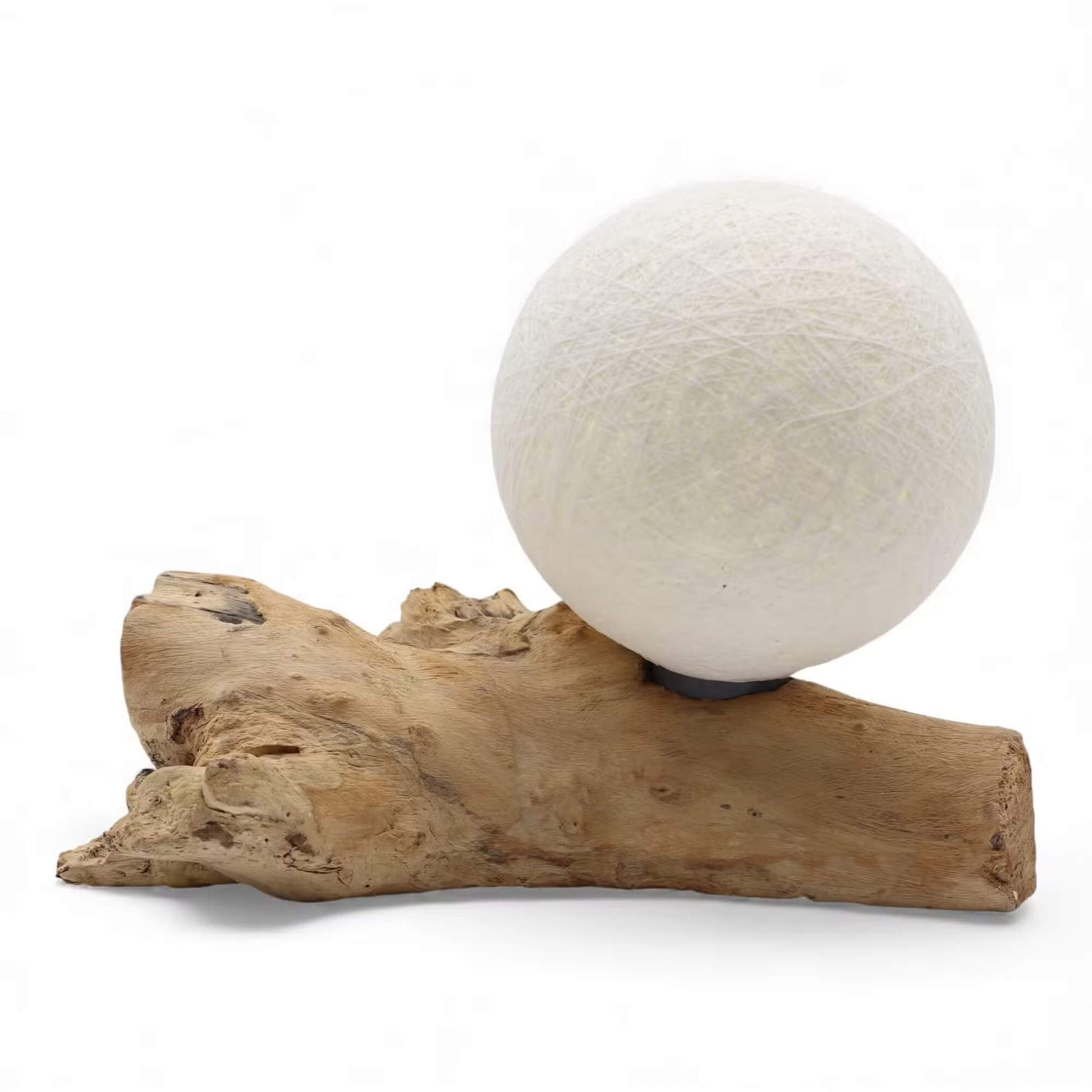 Lampe sphère ivoire tissée éteinte sur longue branche de bois flotté sur fond blanc