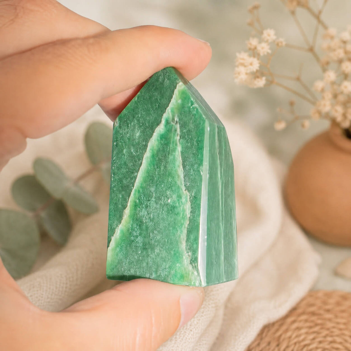 Pointe d'aventurine verte veinée tenue entre les doigts