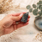 Pointe de lapis-lazuli aux veines bleues tenue entre les doigts