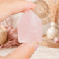 Pointe de quartz rose tenue entre les doigts