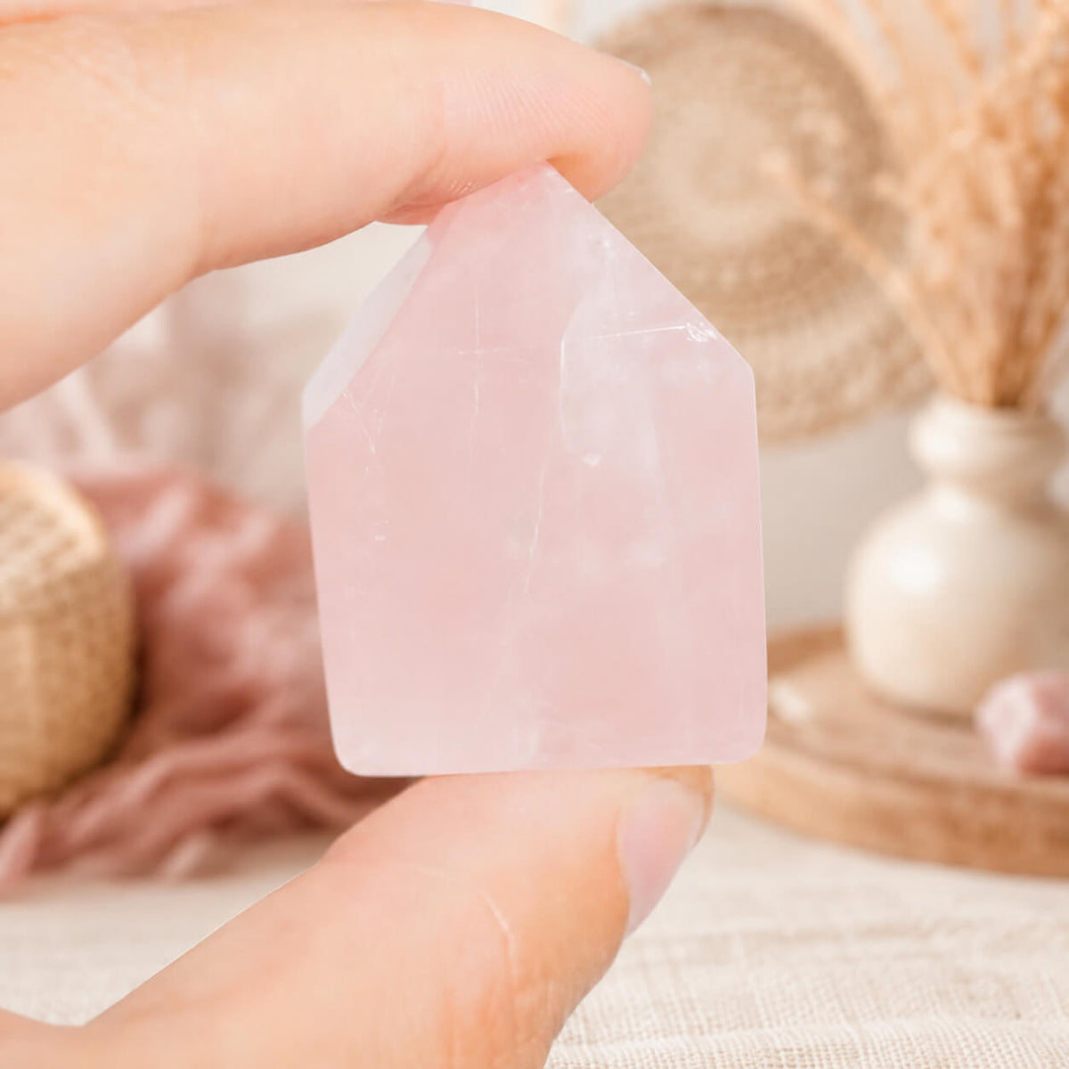 Pointe de quartz rose tenue entre les doigts