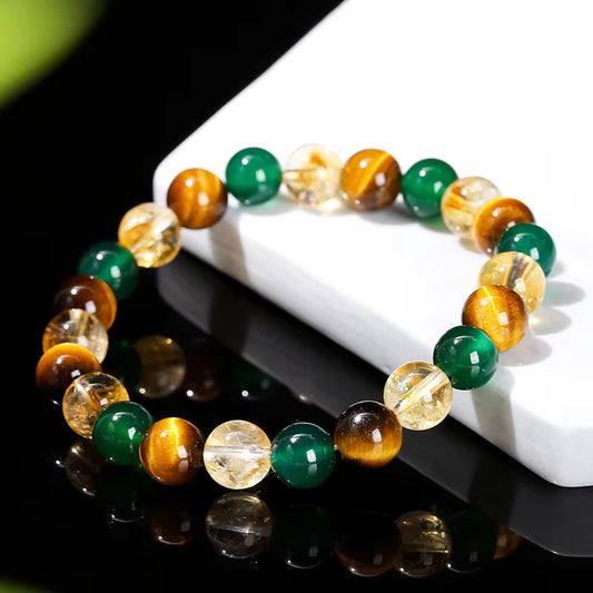 Détail des perles de 8mm en œil de tigre, agate verte et cristal sur support blanc.