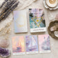 Boîte et cartes du jeu d'oracle Ethereal Waters avec illustrations de voiliers et phare