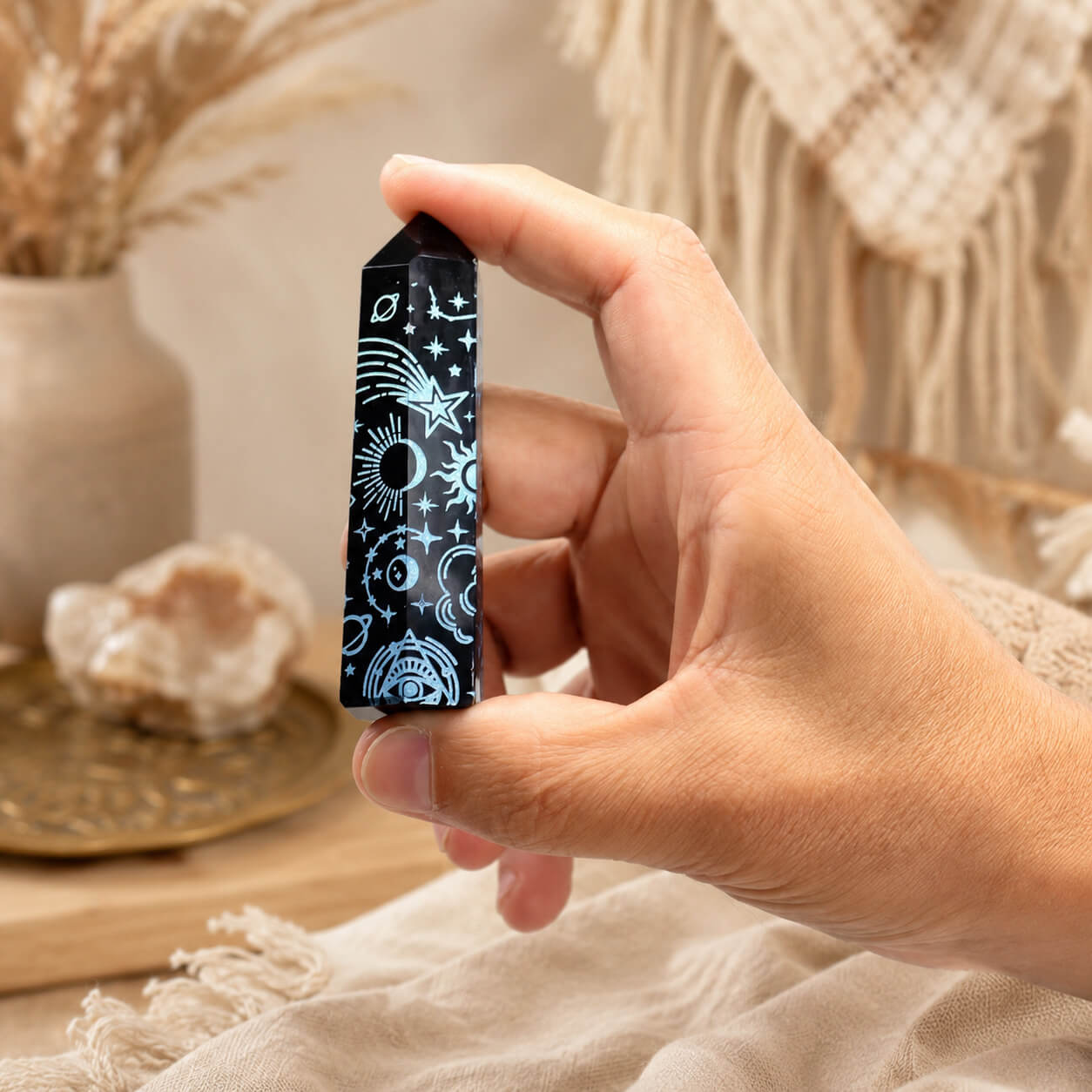 Pointe d'obsidienne noire gravée d'une étoile filante et de planètes en bleu ciel, tenue en main