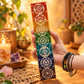 Porte-encens en pierre à savon de 26 cm tenu à la main, montrant les symboles des sept chakras gravés dans des médaillons clairs