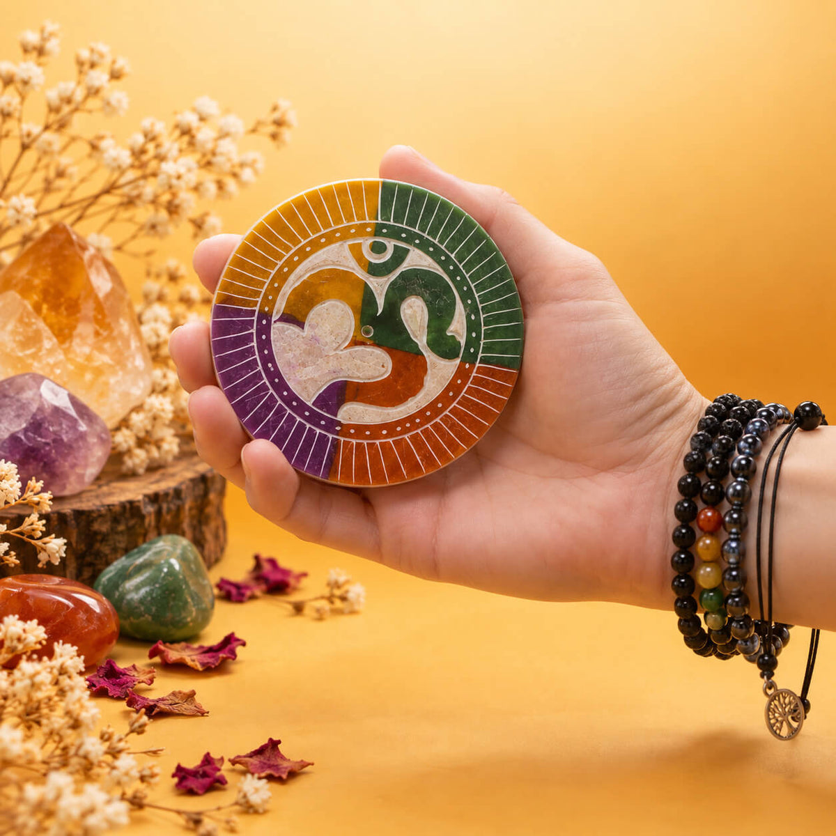 Disque porte-encens Om en pierre à savon de 8 cm tenu dans la main, avec le trou pour bâtonnet au centre du symbole