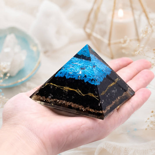 Pyramide en orgonite tenue en main avec éclats de turquoise et base de tourmaline noire