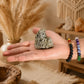 Pyrite naturelle grand format tenue dans une main avec bracelets en pierres naturelles.