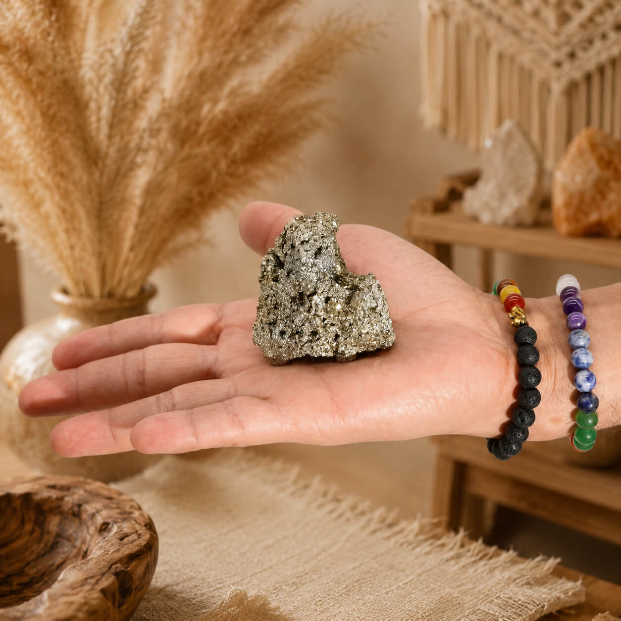Pyrite naturelle grand format tenue dans une main avec bracelets en pierres naturelles.