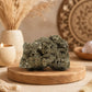 Pyrite naturelle brute grand format à l'éclat doré métallique posée sur socle en bois.