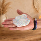 Quartz Aura Angélique tenu dans une main avec bracelets en pierres naturelles