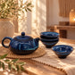 Théière et tasses du service en céramique bleu nuit, quatre tasses empilées à côté