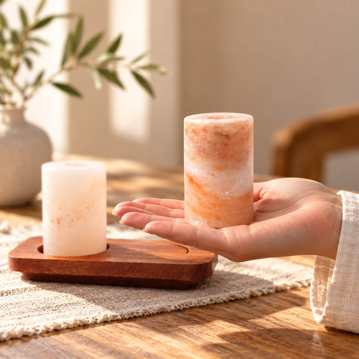 Verre à shot en sel de l'Himalaya tenu en main, à côté de son support en bois