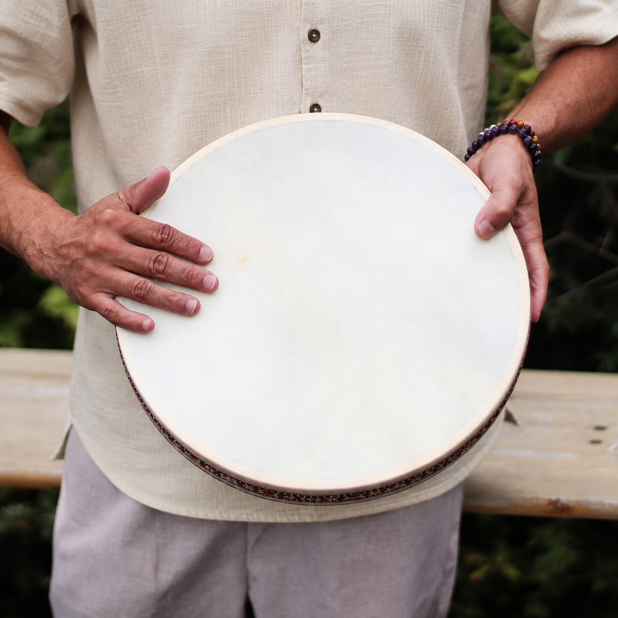 Tambour chamanique océanique 35 cm tenu à deux mains, prêt à être joué.