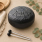 Vue trois quarts du tongue drum noir 16cm révélant le bombé de la coupole et les gravures argentées du mandala.