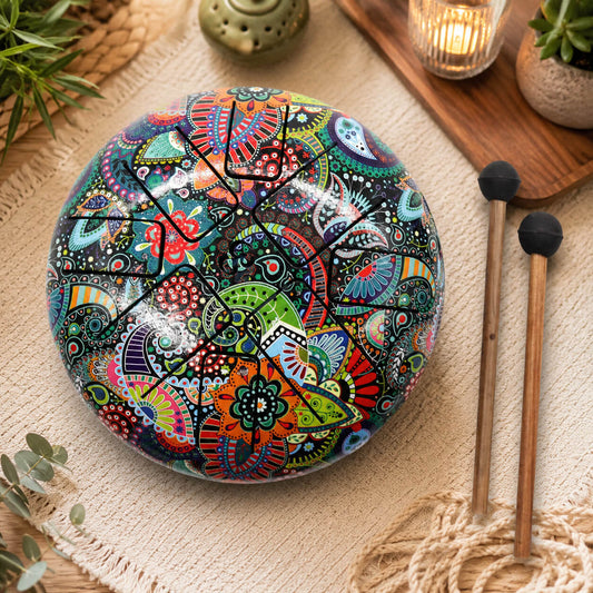 Tongue drum 18cm aux motifs paisley multicolores avec symbole Om et deux mailloches en bois sur tapis macramé