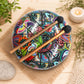 Vue de dessus du tongue drum 18cm paisley multicolore avec ses huit langues mélodiques et mailloches en bois croisées.