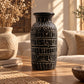 Vase droit en terre cuite brun foncé orné de frises grecques crème en relief, posé sur une table basse