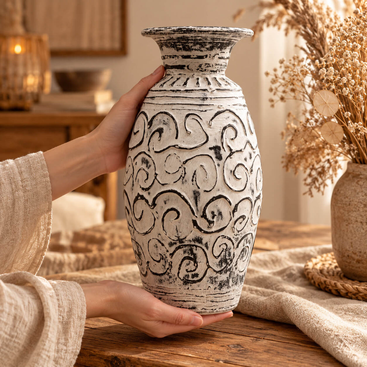 Mains tenant le vase crème décoré de spirales en relief soulignées de noir